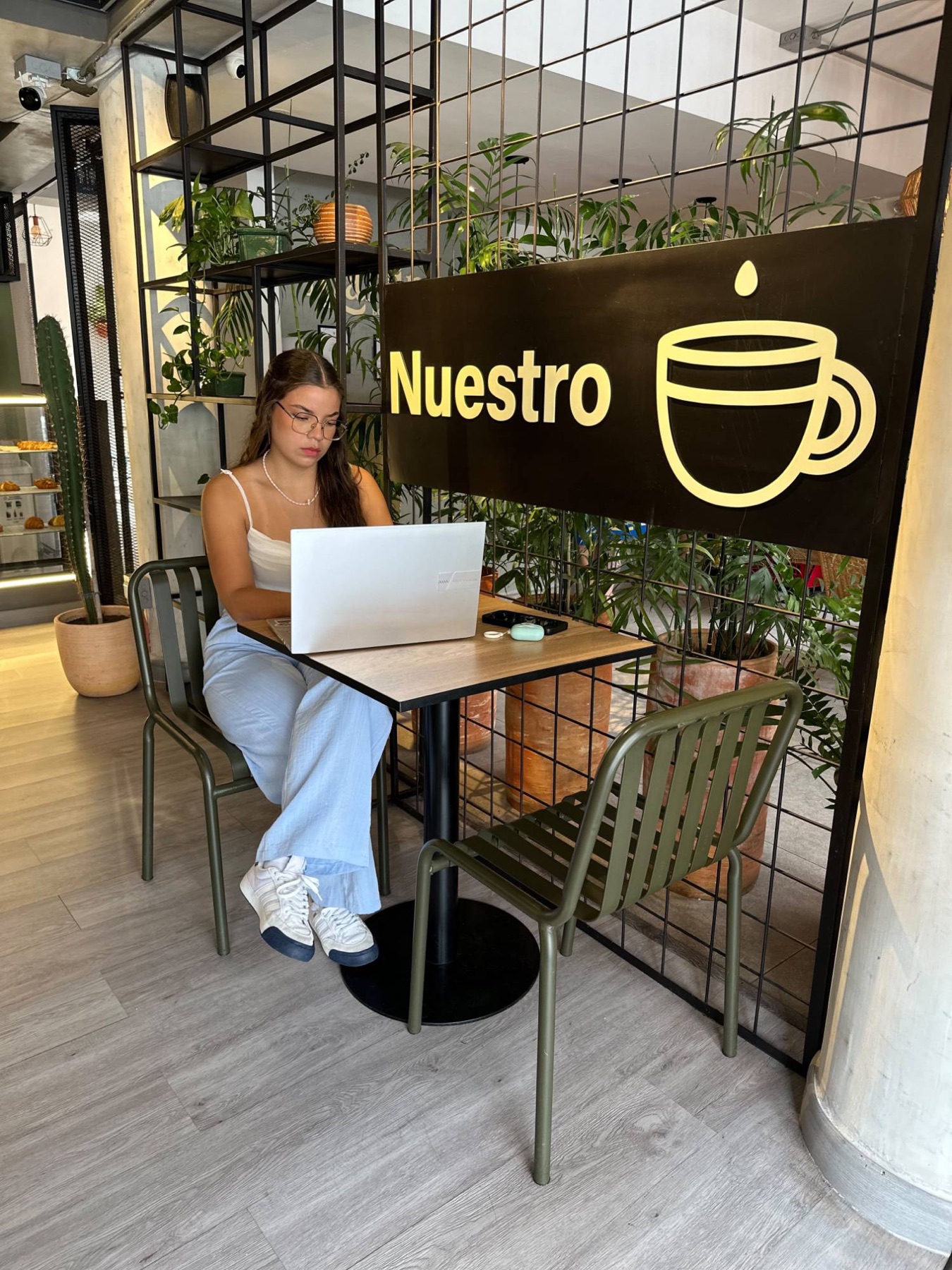 A guest working on her laptop in Nuestro Coffee, under the café sign.
