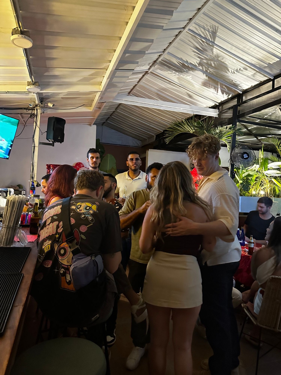 A crowd gathered at the rooftop bar, two guests greeting each other.