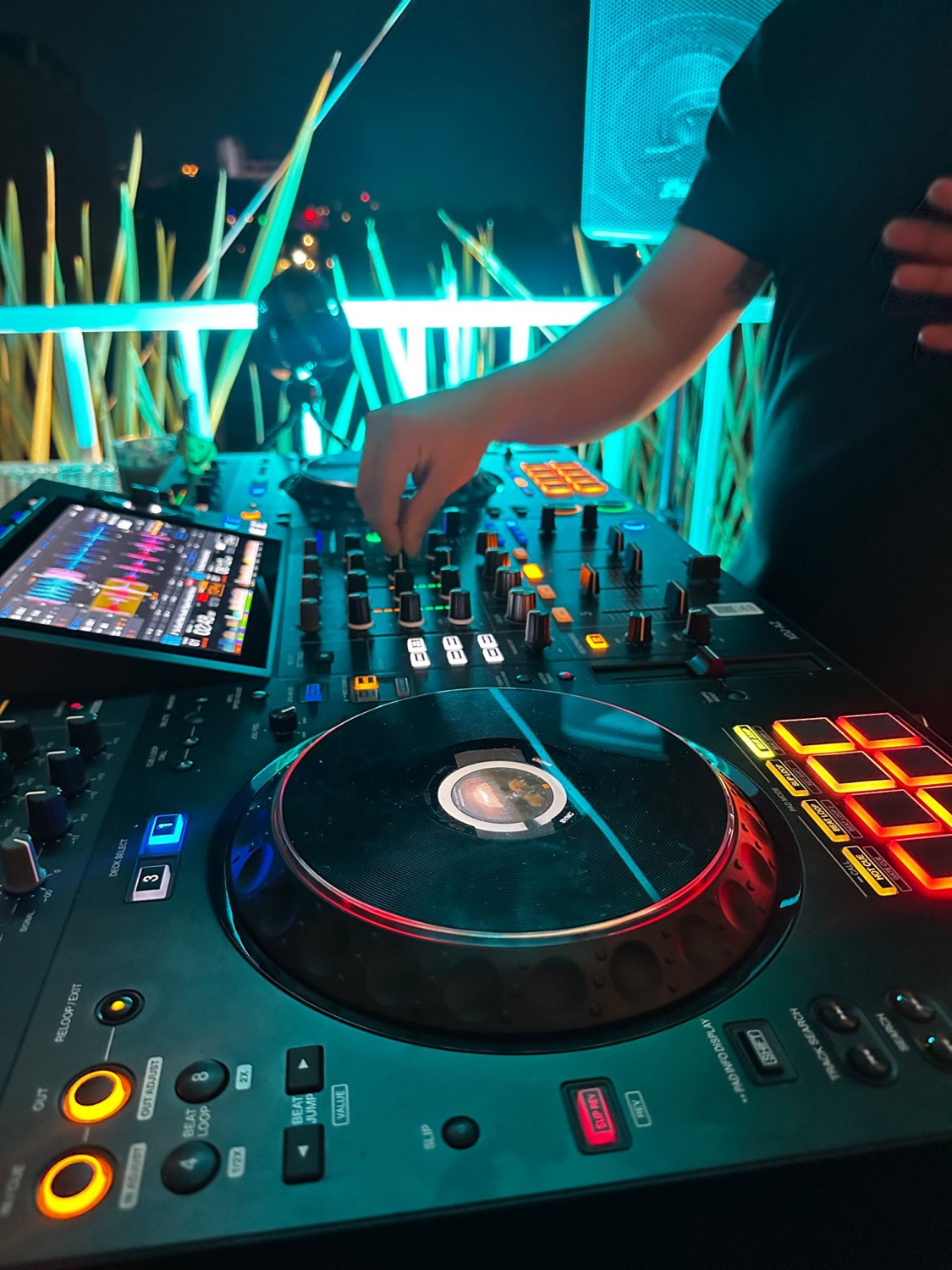 A close view of the DJ decks lit teal on the rooftop.