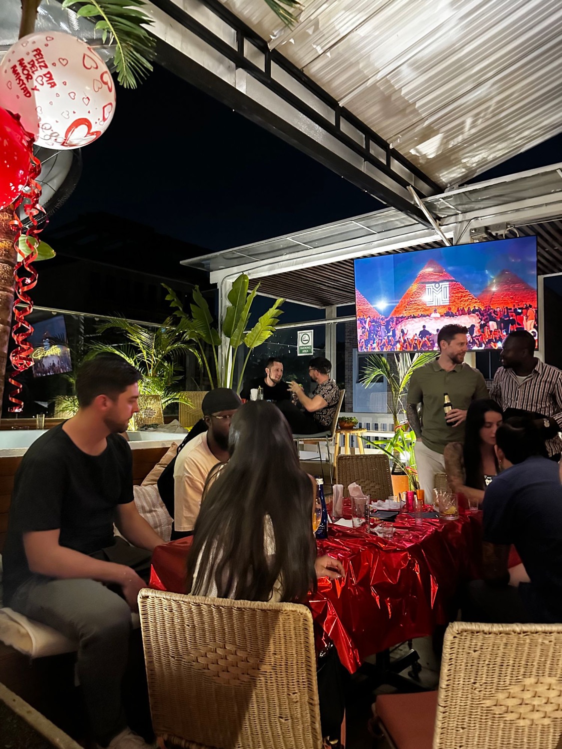 Guests at tables on the rooftop at night, balloons overhead.