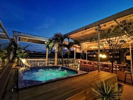 The rooftop jacuzzi and lounge at blue hour, palms lit.
