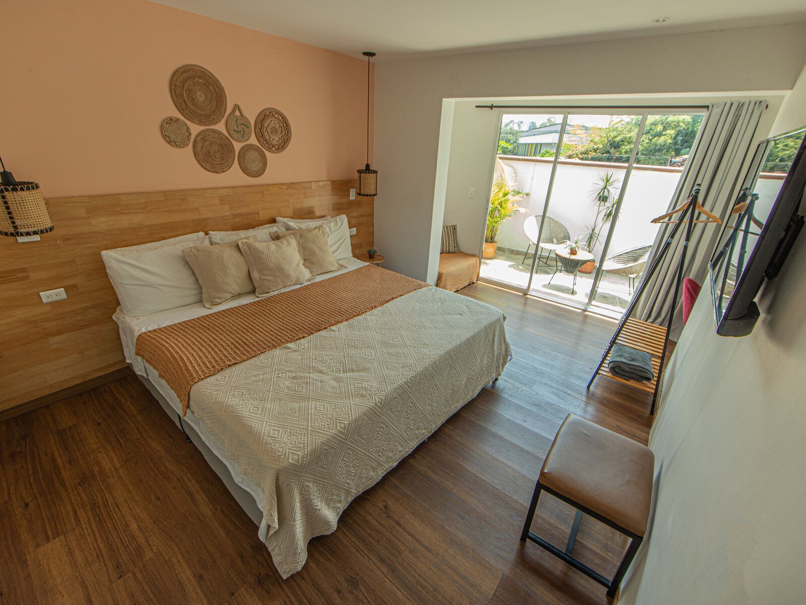 A bright room with a king bed and woven wall baskets.