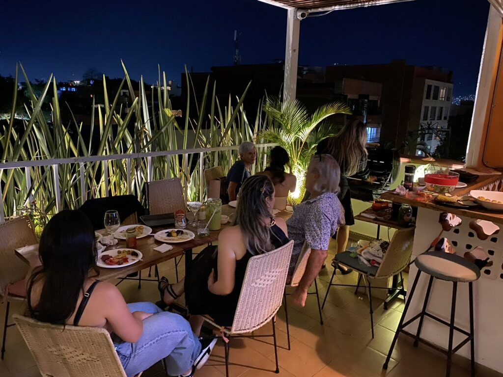 Guests and members around a long table on the rooftop of La Martina for a community dinner.