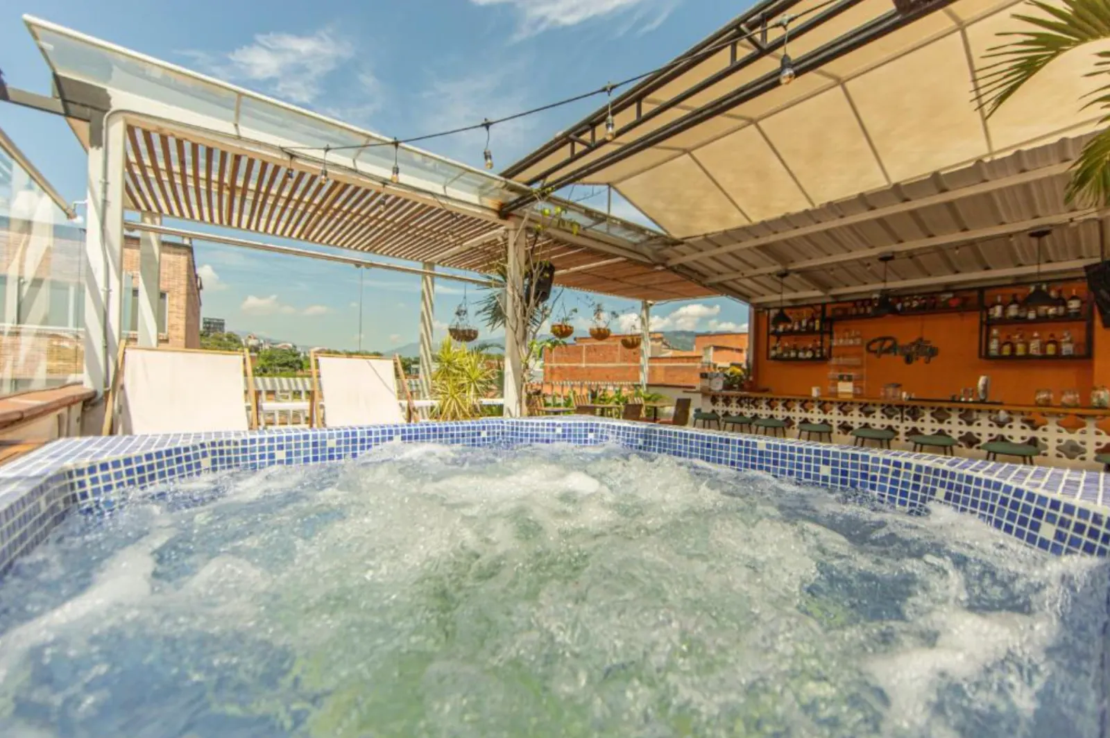 The rooftop jacuzzi bubbling in daylight, the bar and hills behind.