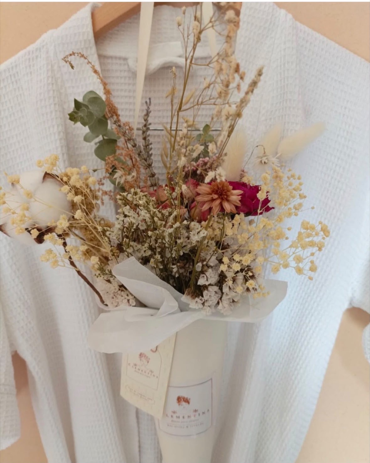 A waffle robe on a hanger with a bouquet of dried flowers.