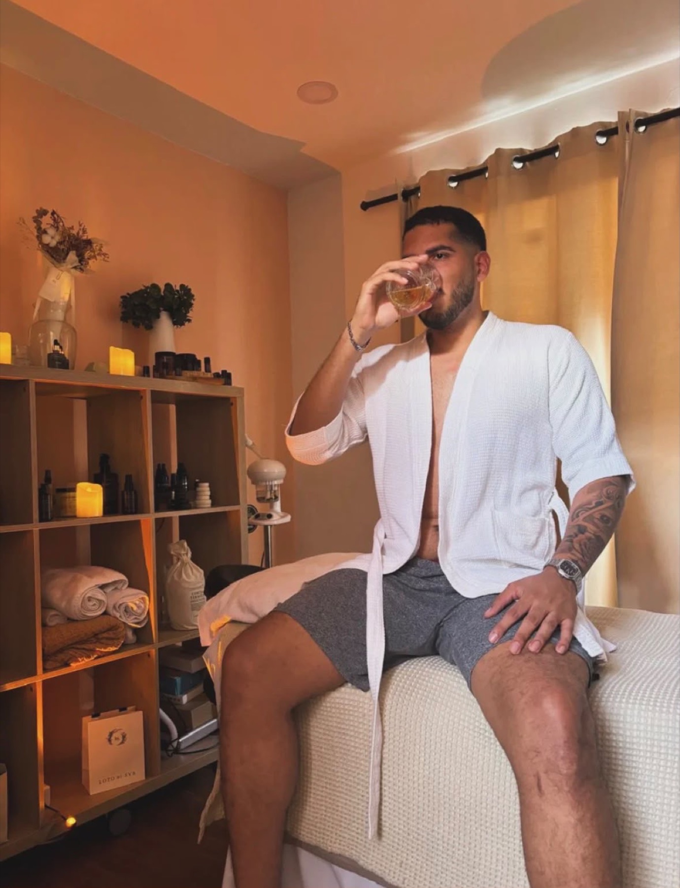 A guest in a waffle robe with a drink after his treatment.