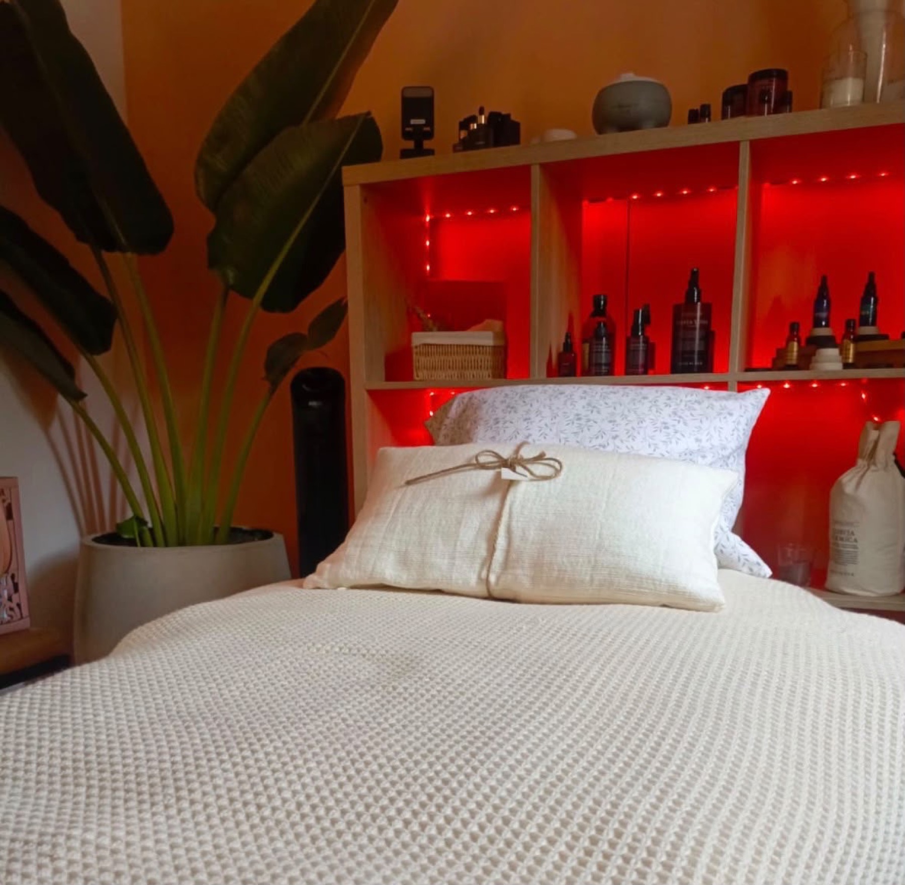 The treatment bed made up in waffle cotton, oils on lit shelves behind.